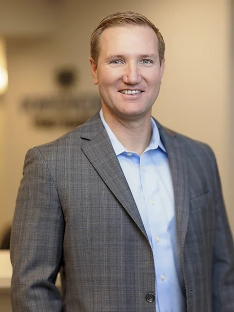 Dr. Joshua Perry, prosthodontist, in a grey blazer in the practice.