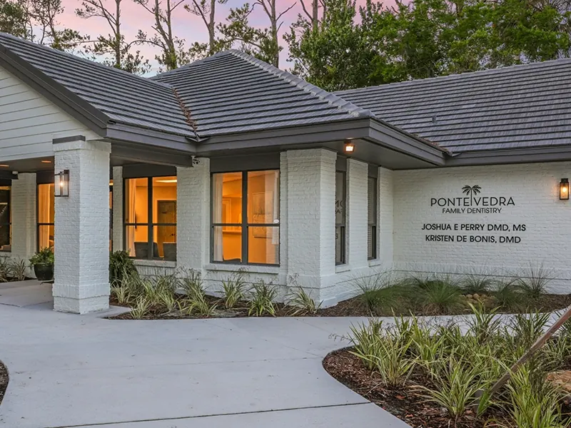 The practice's sign on its white brick wall, naming Joshua E. Perry, DMD, MS and Kristen De Bonis, DMD.