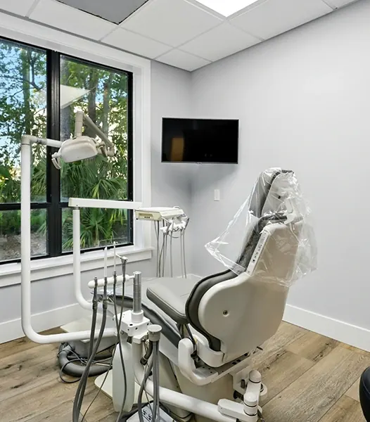 A treatment room with a large window and a ceiling-mounted screen.